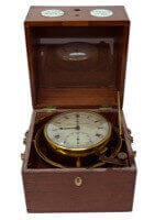 A wooden box opened with a clock like mechanism inside of it.